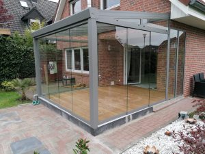 Aluminium-Terrassendach mit Glasschiebewänden an einem Wohnhaus
